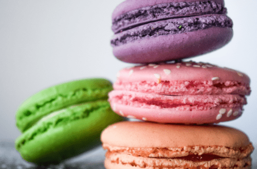 purple pink orange green macaron cookies stacked on each other close up zoom in shot rainbow national cookie day