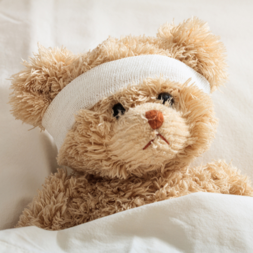 teddy bear in bed with bandage on head with illness